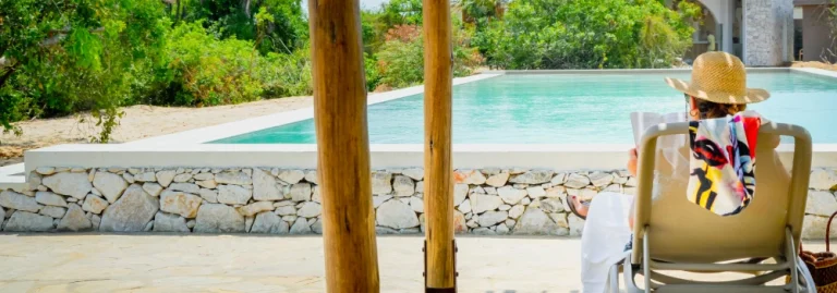 Guest relaxing on a lounger and reading a book by the scenic swimming pool at Hola Africa.