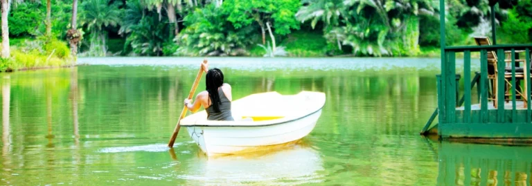 Guest enjoying a peaceful boat ride on a calm river surrounded by lush green trees at Hola Africa.